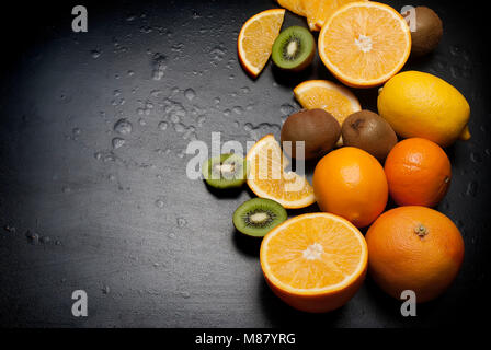 Vielzahl von frischen Zitrusfrüchten auf dunklem Hintergrund aus Schichten von Kiwi und Orangen, kopieren Raum Stockfoto