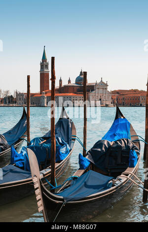Drei schwarzen gondeln zu Beiträge gebunden am Ufer an der Piazzetta di San Marco in Venedig, flankiert von hohen camponile Turm der Renaissance und der Katholischen Kirche Stockfoto