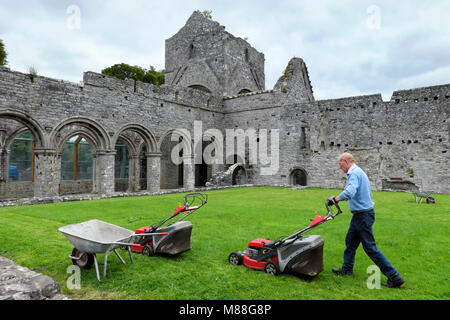 Ein alter Mann/Hausmeister/Hauswart mäht den Rasen, Boyle Abbey, Sycamore Crescent, Boyle, County Roscommon, Irland Stockfoto