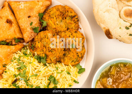 Zwiebel Bhajis und Samosas mit Reis Pilaw auf grauem Hintergrund mit Naan Brot und Mango Chutney Stockfoto