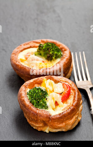 Yorkshire Puddings gefüllt mit Brokkoli und Rührei auf schwarzen Stein Hintergrund Stockfoto