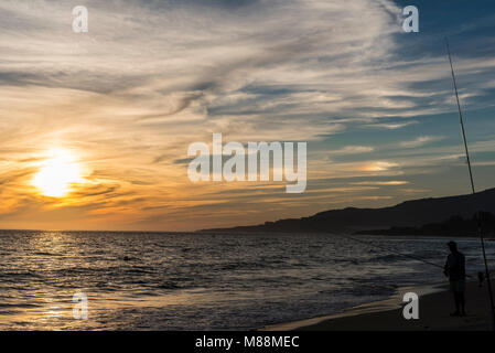 Mann beim Fischen im Meer bei Sonnenuntergang Stockfoto