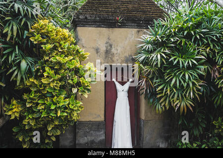 Lange weiße Hochzeit Kleid hängen draußen in Bali Garden Stockfoto