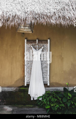 Lange weiße Hochzeit Kleid hängen außerhalb der traditionellen Bali Haus Stockfoto