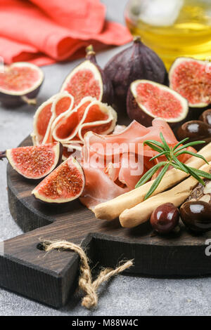 Vorspeise von Schinken, Salami, Brot, Sticks, Kalamata Oliven und Feigen auf einem Schneidebrett. Italienische Antipasti. Selektiver Fokus Stockfoto