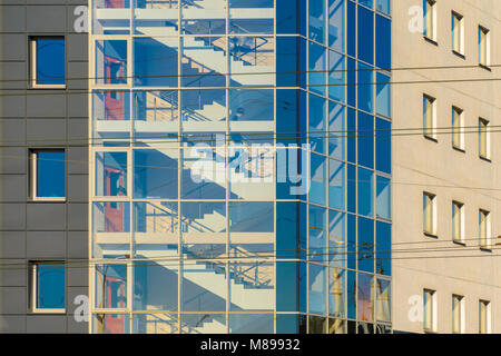 Abbildung eines Mannes im Treppenhaus eines Bürogebäudes hinter einer Glasfassade. Treppe mit Glasfassade in einem Büro Gebäude Architektur Backgroun Stockfoto