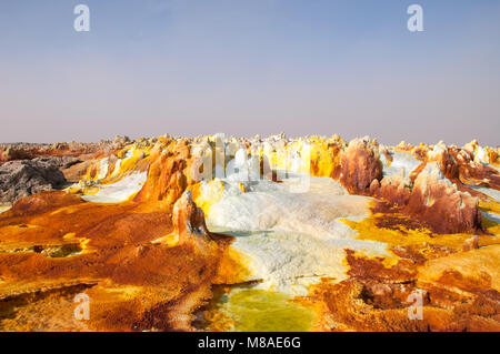 Ist das Feld orange Schwefelsäure Vulkane giftige Gas Wolken, schwefelablagerungen sind Weiß und Grün in der Wüste Danakil, das Becken in der Ferne Stockfoto