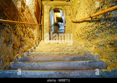 Ferner verschwommenes Bild der Person in der Nähe der Oberseite der alte Steintreppe in Golden low light mit runden hölzernen Handlauf oben auf jeder Seite. Stockfoto