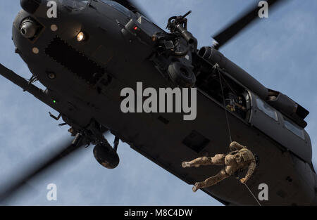 Eine pararescueman stößt aus HH-60G Pave Hawk Hubschrauber, die 66Th Rescue Squadron zugewiesen, während der Ausbildung auf der Nellis Air Force Base, Nevada, Feb 22, 2018. Die Pave Hawk ist ein mittlerer Hubschrauber mit Doppelrotor von Air Combat Command, Pacific Air Forces, Bildung und Ausbildung, der US-Luftstreitkräfte in Europa, Air National Guard und der Air Force Reserve Command betrieben. (U.S. Air Force Stockfoto