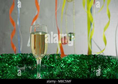 Weihnachten und Neujahr Grußkarte Schablone aus goldenen und grünen Lametta mit roten Weihnachtskugeln, red ribbon, orange Kerze und zwei Gläser von c Stockfoto