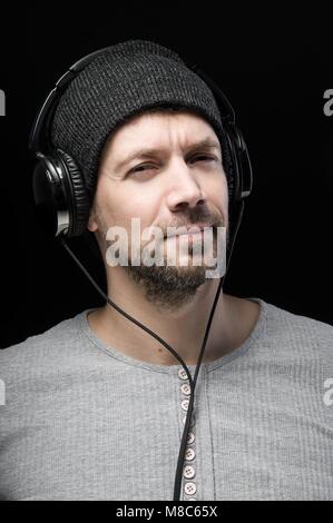 Junger Mann in grauen Bluse Musik hören mit Kopfhörern auf dem Kopf Stockfoto