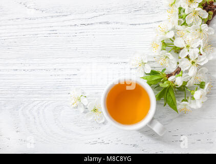 Tasse grünen Tee und Niederlassung von blossom Cherry auf weissem Holztisch. Stockfoto