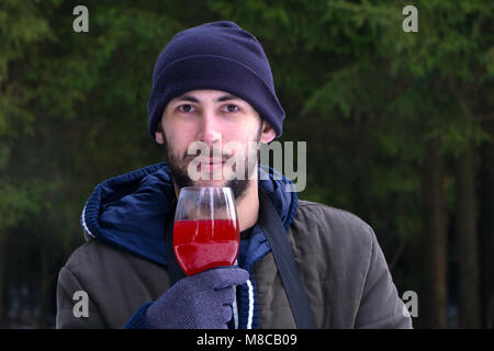 Der Kerl steht in der Natur. Er hielt die Weingläser in unseren Händen. Stockfoto