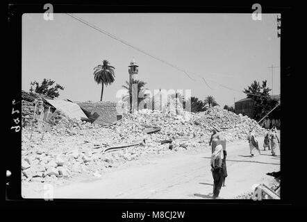 Dieses Bild aus dem Jahr 1938 zeigt die Hauptstraße Jerusalem-Galiläa, die durch Dschenin führt, mit Trümmern aus der Dynamitierung, die die Auswirkungen militärischer oder politischer Aktivitäten während dieser Zeit widerspiegeln. Stockfoto