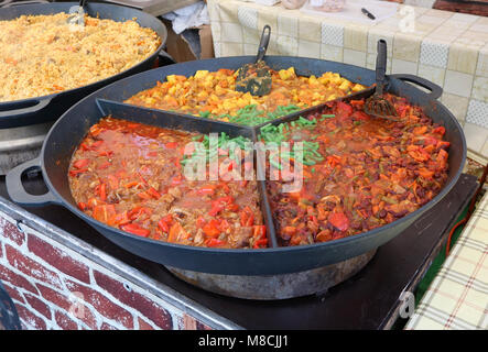 Schnelle Street Food - geschmorte Weisse, Paprika, Tomaten und Kartoffeln mit gekochtem Rindfleisch in grossen Pfanne. Frühjahrsmesse Urlaub Tag Außenaufnahme Stockfoto