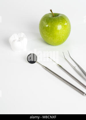 Grüner Apfel und Dentalwerkzeuge isoliert auf weiss Stockfoto