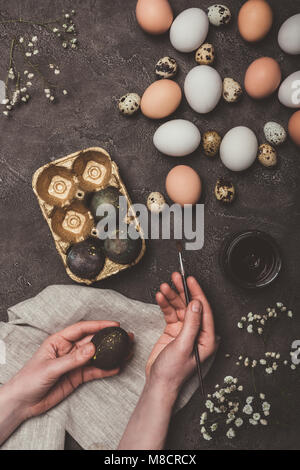 7/8-Ansicht des Menschen Malerei Ostereier und setzen Sie in Fach, Blumen, Wachteln und huhn eier in der Nähe von Stockfoto