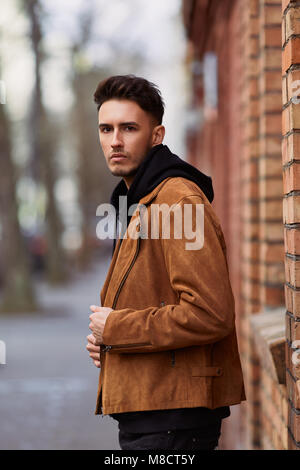 Modell Mann stand in der Nähe der Wand und schaut auf seine Uhr Stockfoto