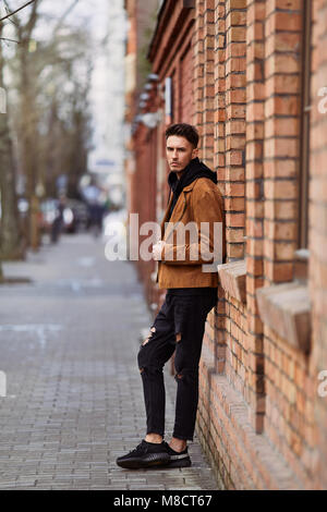 Modell Mann stand in der Nähe der Wand und schaut auf seine Uhr Stockfoto