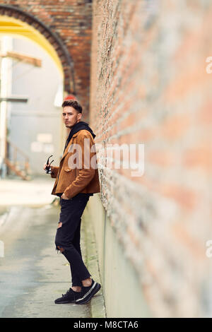 Modell Mann stand in der Nähe der Wand und schaut auf seine Uhr Stockfoto