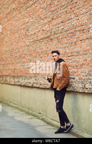 Modell Mann stand in der Nähe der Wand und schaut auf seine Uhr Stockfoto