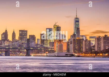 New York City, USA Skyline auf den East River und die Brooklyn Bridge in der Abenddämmerung. Stockfoto