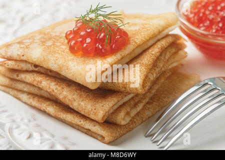 Die traditionellen russischen Pfannkuchen (BLINI) mit Lachskaviar auf einem weißen Teller. Selektiver Fokus Stockfoto