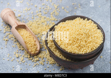 Raw organic Couscous in eine Schüssel auf dem Tisch. Selektiver Fokus Stockfoto