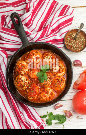Hackfleischbällchen in Tomatensauce mit Gewürzen und Knoblauch in einem schwarzen Gusseisen Skillet. Selektiver Fokus Stockfoto