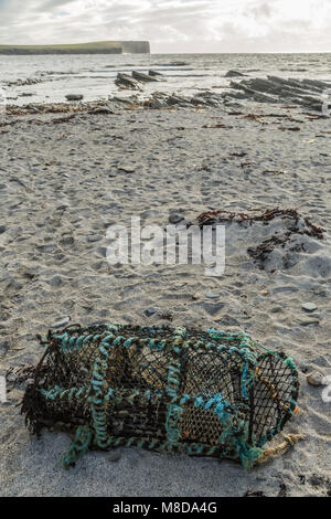 Vintage Lobster Pot oder creel, der am Ufer des Meeres mit weit entfernten Klippen abgebrochen Stockfoto