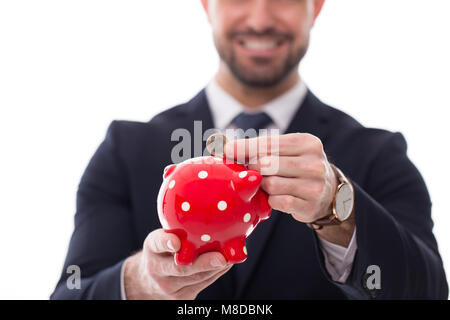 Mann in formale Abnutzung stellen ein Euro Münze in Sparschwein isoliert Stockfoto
