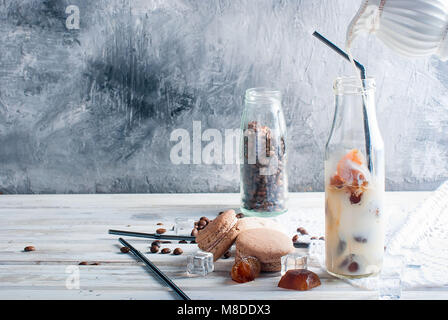 Kaffee Eis in der Flasche, Makronen,, Stücke von Schokolade und Kaffee Bohnen auf einem dunklen Tabelle Stockfoto