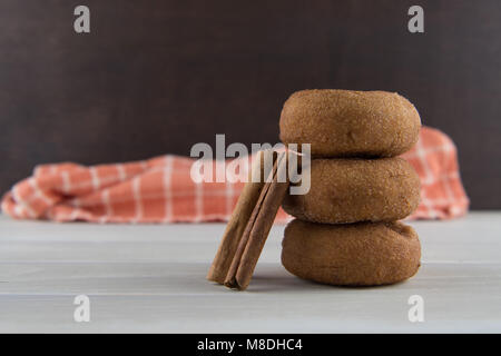 Zimtstangen lehnte sich gegen Donuts im Stapel Stockfoto