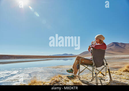 Frau in camping Stuhl sitzen, die Aussicht, Salar de Chalviri, Chalviri, Oruro, Bolivien, Südamerika Stockfoto