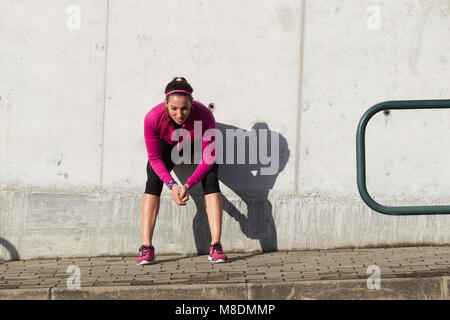 Junge Frau gegen die Wand hocken Stockfoto