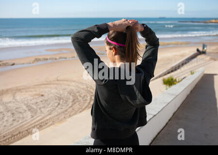 Ansicht der Rückseite des junge Frau am Strand binden Haar in Pferdeschwanz, Carcavelos, Lisboa, Portugal, Europa Stockfoto