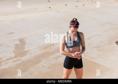 Junge Frau am Strand bei Fitness Tracker, Carcavelos, Lisboa, Portugal suchen, Europa Stockfoto