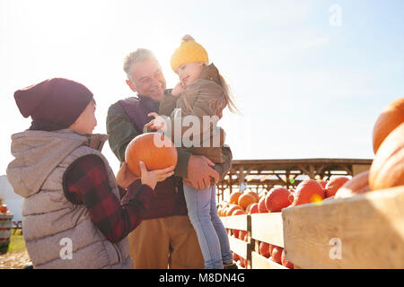 Mädchen und Bruder mit Großvater Auswahl Kürbisse in Pumpkin Patch Feld Stockfoto