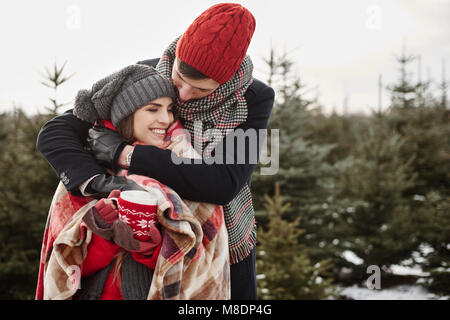 Romantische junge Paar in christmas tree forest in Decke gewickelt Stockfoto