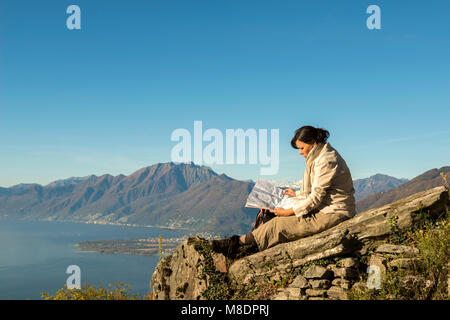 Frau entspannen Sie sich auf einem Berg mit alpinen Lago Maggiore im Hintergrund, im Tessin, Schweiz Stockfoto