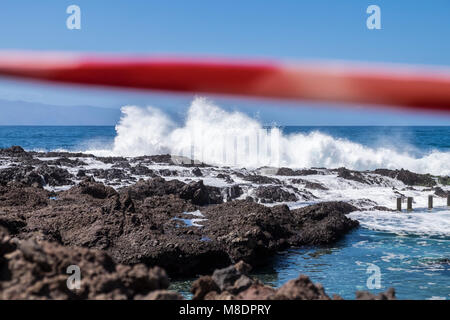 Rotes Klebeband über den Felsen, um zu verhindern, dass die Leute an der Küste, wo es sehr raue See brechen über Felsen und felsenpools an der Küste zu einem Stockfoto