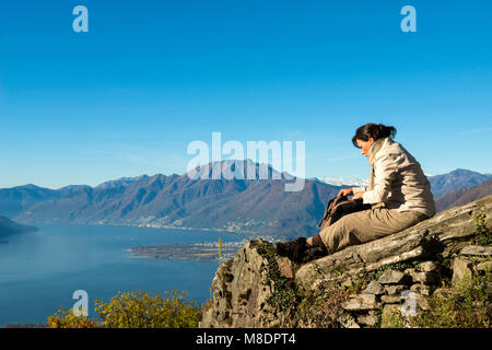 Frau entspannen Sie sich auf einem Berg mit alpinen Lago Maggiore im Hintergrund, im Tessin, Schweiz Stockfoto