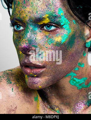 Studio Portrait von Blue eyed junge Frau mit glitzerndem mehrfarbige Pulver auf dem Gesicht Stockfoto