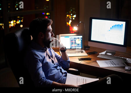 Junge Unternehmer starrte auf Computer im Büro Schreibtisch bei Nacht Stockfoto