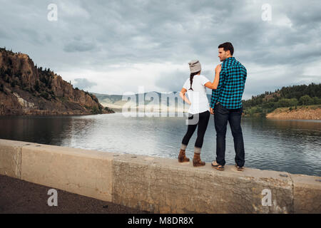 Paar stehend auf Wand neben Dillon Stausee, Anzeigen suchen, Ansicht von hinten, Silverthorne, Colorado, USA Stockfoto