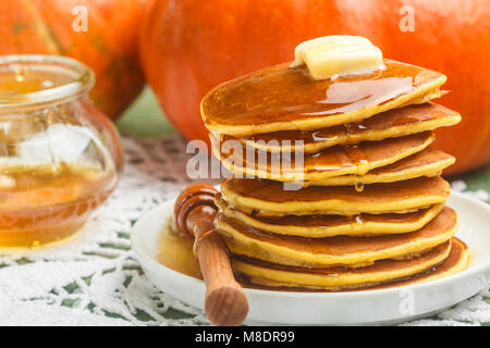 Hausgemachte Kürbis Pfannkuchen mit Butter und Honig auf einem weißen Teller auf dem Tisch. Nützliches, leckeres Frühstück. Selektiver Fokus Stockfoto