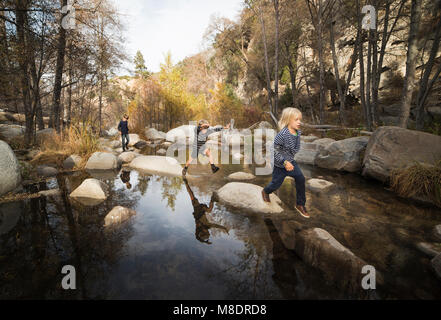 Kinder spielen auf Felsen im Fluss, Lake Arrowhead, Kalifornien, USA Stockfoto
