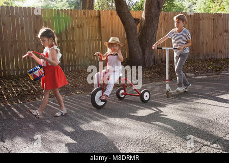 Drei Kinder im Mini Parade, klappert drum, Reitferien, Dreirad und Roller Stockfoto