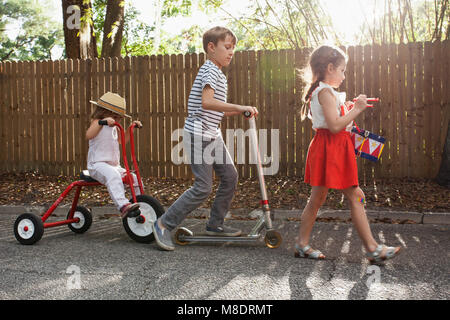 Drei Kinder im Mini Parade, klappert drum, Reitferien, Dreirad und Roller Stockfoto