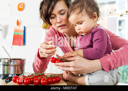 Mutter und Tochter in der Küche, Sortieren durch Tomaten auf den Küchentisch Stockfoto
